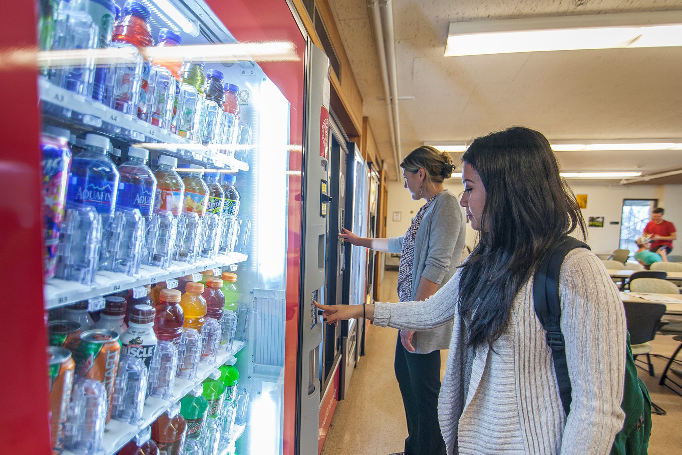two women spend break time getting snacks and drinks from vending machines